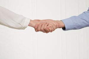 A handshake with hands on top (body language: leading handshake)