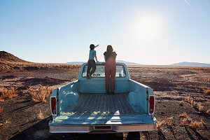 Mutter und Sohn stehen auf der Ladefläche eines Pick-ups (Wüstenlandschaft, Arizona, USA)