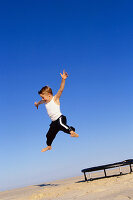 A boy jumping on a trampoline on a beach