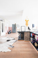 Open-plan living space with log-burner and cowhide rug on gallery