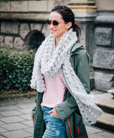 A woman wearing a crocheted scarf with a scallop pattern