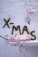 Schriftzug x-mas aus Moos als weihnachtliche Aussendekoration an Wand