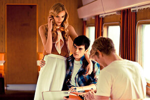 A young woman with two young men on a train