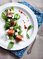 Figs, gorgonzola and spinach salad with port dressing on a white plate