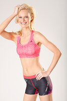 A young blonde woman wearing a pink sports bra and shorts