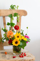 Spätsommerlicher Strauß mit gelben Zinnien auf Holzstuhl