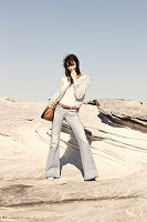 A brunette woman with a shoulder bag wearing a white top, a jacket and jeans