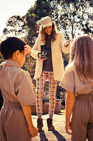 Junge Frau mit Mütze und Kinder in Uniform beim Fotoshooting