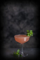 A Cosmopolitan cocktail decorated with herbs