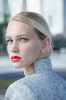 A young blonde woman with red lipstick and a grey top