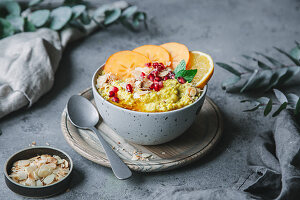 Turmeric and millet porridge with persimmon, orange and pomegranate seeds