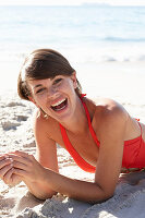 A mature brunette woman on a beach wearing a red bathing suit