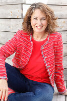 A brunette woman wearing a red top, a red jacket and jeans