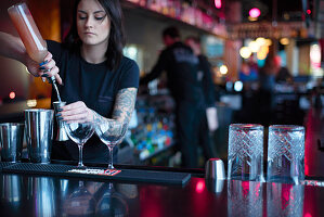 A bartender mixing cocktails at a bar