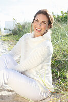 Brunette woman wearing white knit sweater and white trousers
