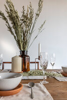 Wooden table set with candle and ears of cereal in apothecary bottle