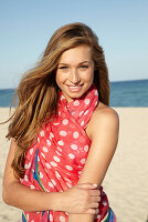 A young blonde woman by the sea wearing a beach towel