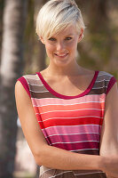 A mature blonde woman with short hair outside wearing a striped top