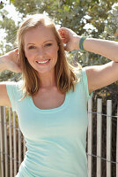 A young blonde woman outside wearing a light-blue top