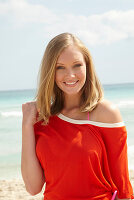 Junge blonde Frau in orangenem Top am Strand