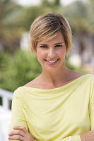 A young blonde woman with short hair outside wearing a yellow top