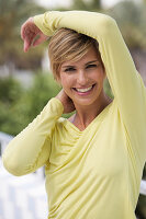 A young blonde woman with short hair outside wearing a yellow top