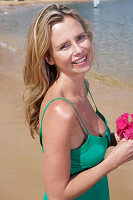 A young blonde woman on a beach wearing a green top