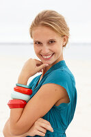 A young blonde woman on a beach wearing a blue summer dress