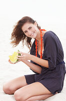 Brünette Frau im lila Strandkleid mit Melone