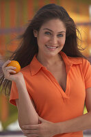 A young brunette woman wearing an orange polo shirt and holding an orange