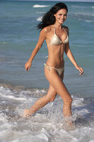Junge brünette Frau im silbernen Bikini am Strand