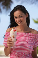 A young brunette woman wearing a red-and-white striped top holding a refreshing drink