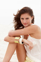 A brunette woman on a beach wearing a white top and shorts