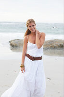 Blond Frau in weißem Sommerkleid am Meer