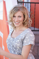 A blonde woman wearing a grey spotted blouse