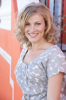 A blonde woman wearing a grey spotted blouse