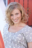 A blonde woman wearing a grey spotted blouse