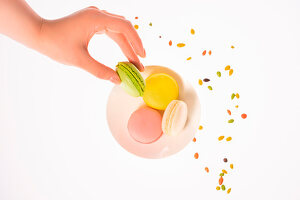 A woman taking a colourful macaron