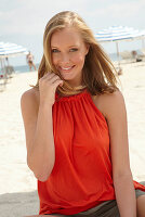 A blonde woman on a beach wearing an orange top