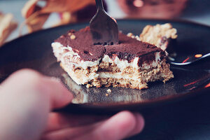 Tiramisu, angebissen, auf Teller mit Gabel