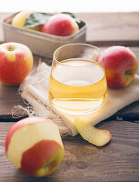 A glass of apple juice, with fresh apples around it