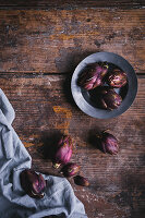 Small violet artichokes on a cloth and a wooden surface