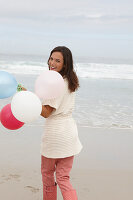 Brünette Frau mit Luftballons in Strickjacke mit kurzen Ärmeln