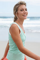 A blonde woman on a beach wearing a turquoise top