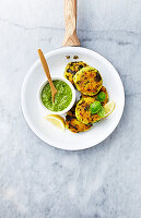 Millet patties with kale and zucchini, served with spinach pesto and lemon vedges