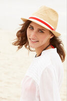 A brunette woman wearing a hat and a white blouse