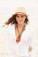 Brünette Frau mit Hut in rotem Bikinioberteil und weißer Bluse