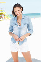 Junge Frau im Jeanshemd und weißen Shorts am Strand