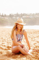 A girl on a beach wearing a hat and a bikini