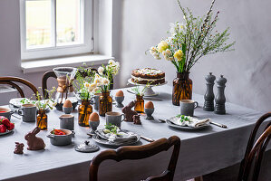 A table laid for an Easter breakfast with boiled eggs, coffee, carrot cake, chocolate bunnies and fruit salad